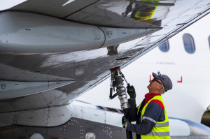 An employee of a ground service company refuels an aircraft. [Credit: Shutterstock/Karolis Kavolelis]